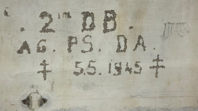 In eine Wand geritzte Buchstaben, Zahlen und Symbole: Erinnerungskultureller Gedankenaustausch im Dokumentationszentrum Obersalzberg im Gedenken an die Besetzung des Berghofs durch Soldaten der 2. französischen Panzerdivision. Initiator war der Generaldelegierte des Souvenir français in Bayern, Pierre Wolff. Im Bunkersystem wurden zwei Lothringerkreuze durch drei Soldaten der Division in die Wand geritzt. Das Kreuz war das Symbol der Panzerdivision, aber auch das Zeichen der französischen Résistance. Landesgeschäftsführer Jörg Raab hob in seinem Grußwort die Bedeutung sowohl des Dokumentationszentrum als auch der nahegelegenen Kriegsgräberstätte Schönau (937 Tote beider Weltkriege) als „Lernorte der Geschichte“ hervor.   